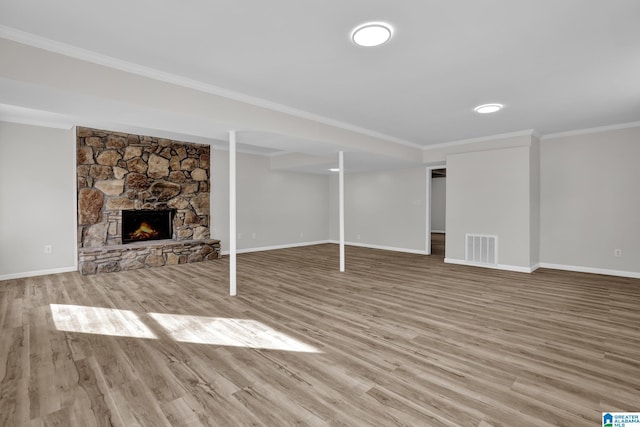 unfurnished living room featuring a fireplace, wood finished floors, visible vents, baseboards, and crown molding