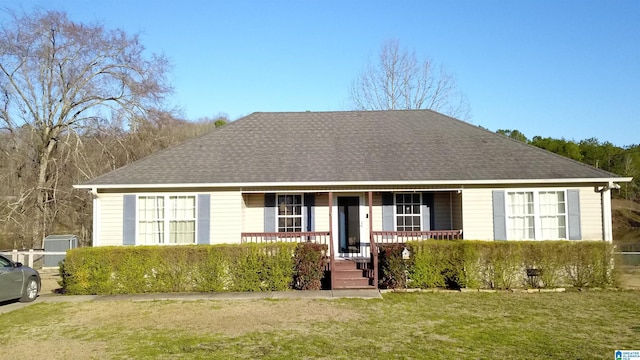 ranch-style home with covered porch, a shingled roof, and a front yard