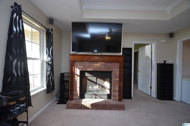 carpeted living room featuring a brick fireplace, baseboards, ornamental molding, and a tray ceiling