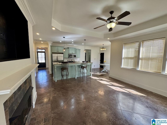 unfurnished living room featuring recessed lighting, a ceiling fan, baseboards, ornamental molding, and a tray ceiling