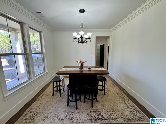 dining room featuring an inviting chandelier, baseboards, visible vents, and ornamental molding