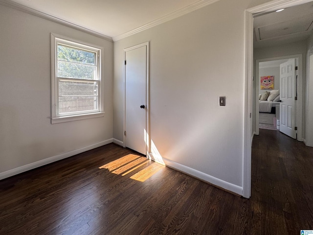 empty room featuring dark wood-style flooring, crown molding, and baseboards