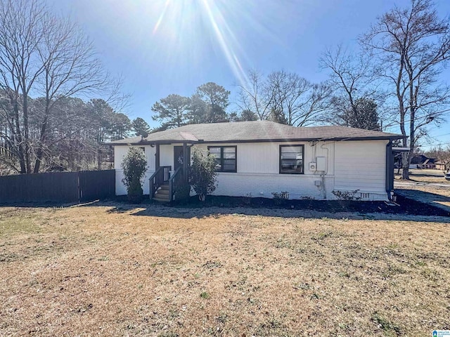 single story home featuring brick siding, fence, and a front lawn