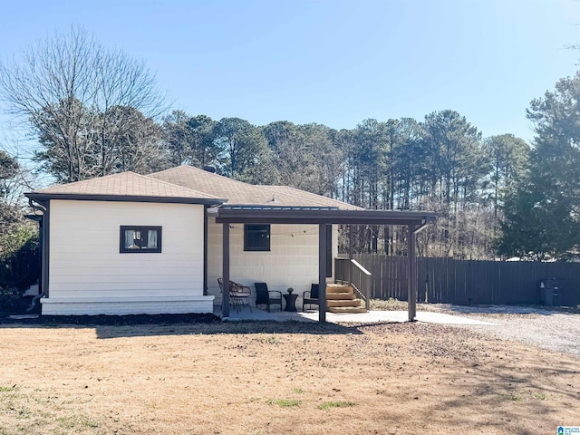 view of front of house featuring a shingled roof, a patio area, and fence