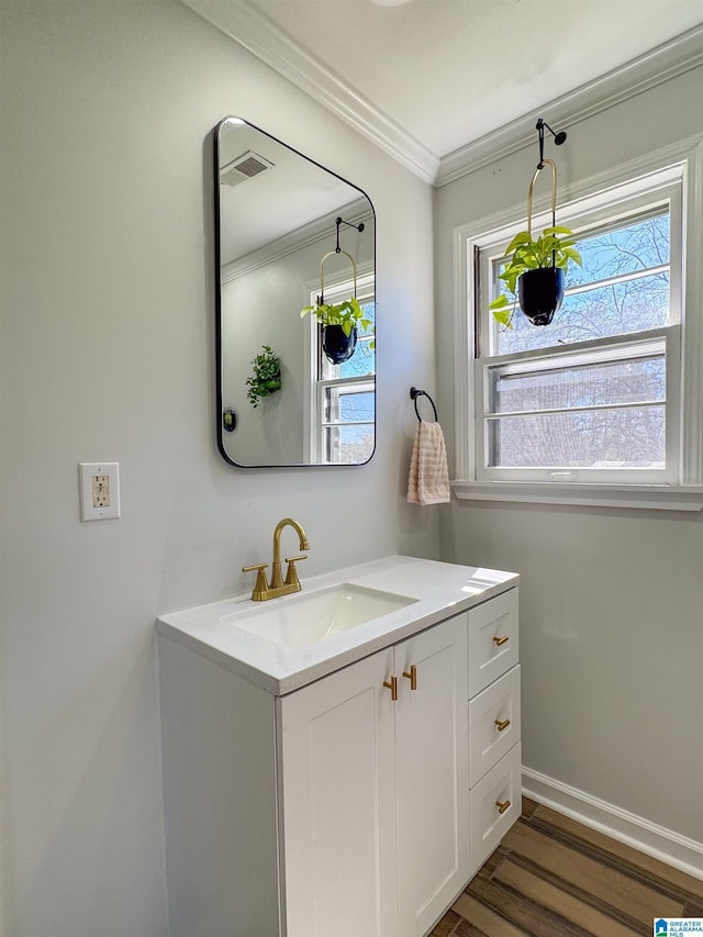 bathroom featuring wood finished floors, vanity, baseboards, visible vents, and crown molding