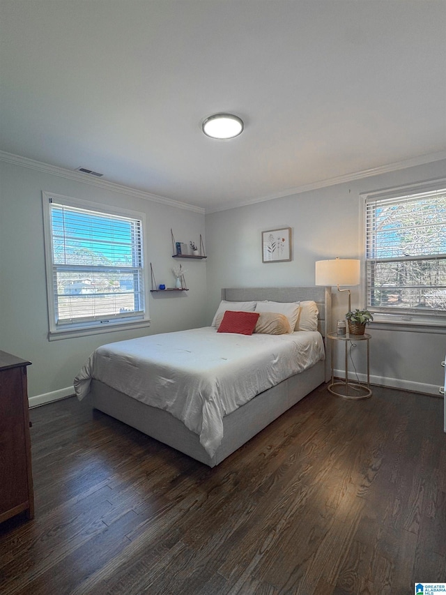 bedroom with dark wood-style floors, visible vents, baseboards, and crown molding