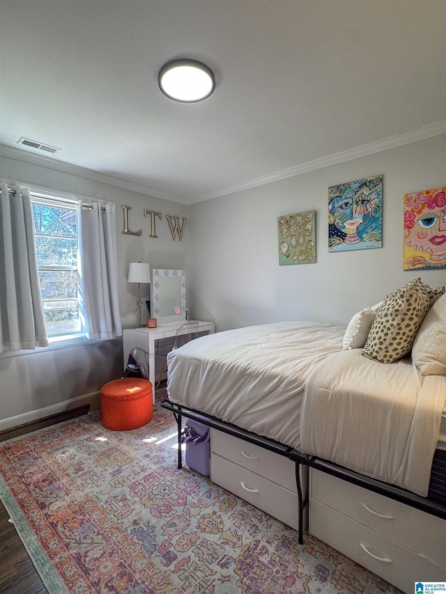 bedroom with baseboards, wood finished floors, visible vents, and crown molding