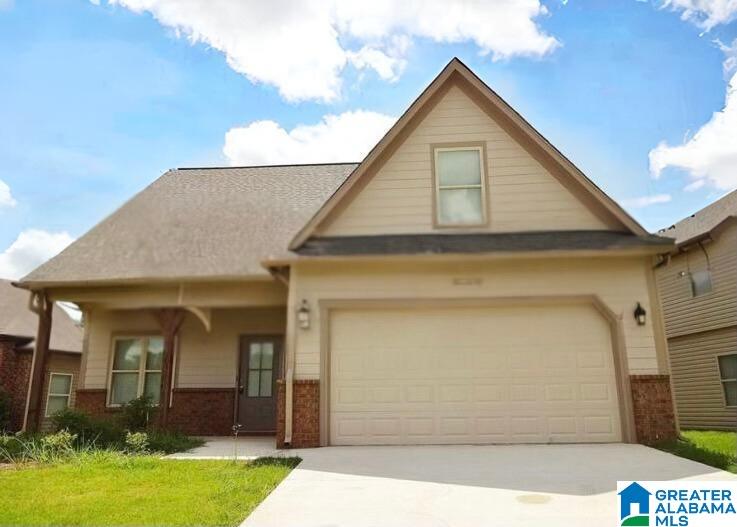 view of front of home with driveway, brick siding, a front lawn, and an attached garage