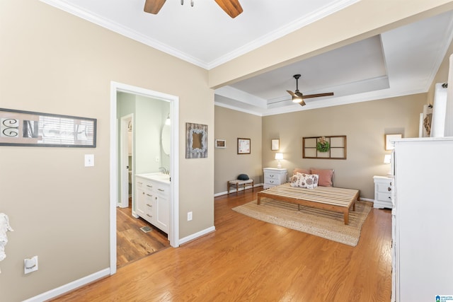 bedroom with a tray ceiling, baseboards, light wood-style flooring, and ornamental molding