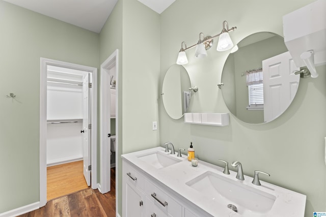 bathroom featuring double vanity, wood finished floors, and a sink