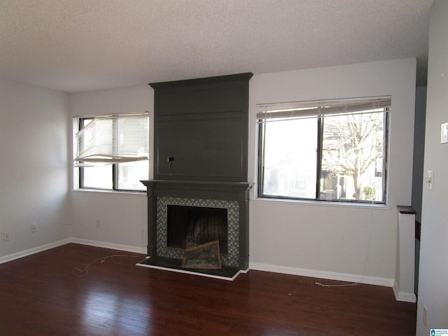 unfurnished living room with wood finished floors, a tile fireplace, and baseboards