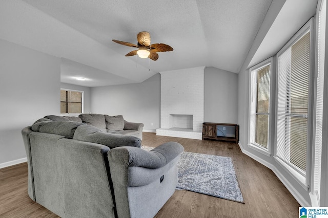 living room featuring baseboards, lofted ceiling, ceiling fan, wood finished floors, and a fireplace