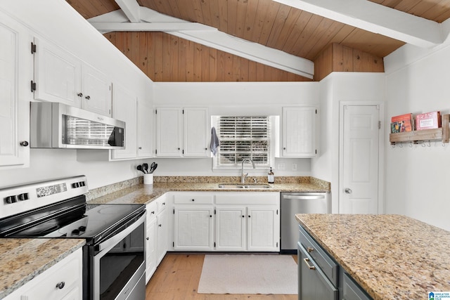 kitchen featuring white cabinets, vaulted ceiling with beams, stainless steel appliances, and a sink