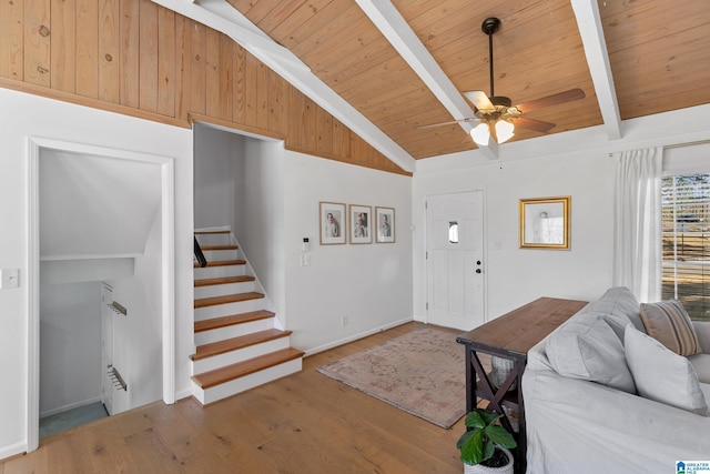 entryway featuring stairway, lofted ceiling with beams, a ceiling fan, wood finished floors, and wooden ceiling