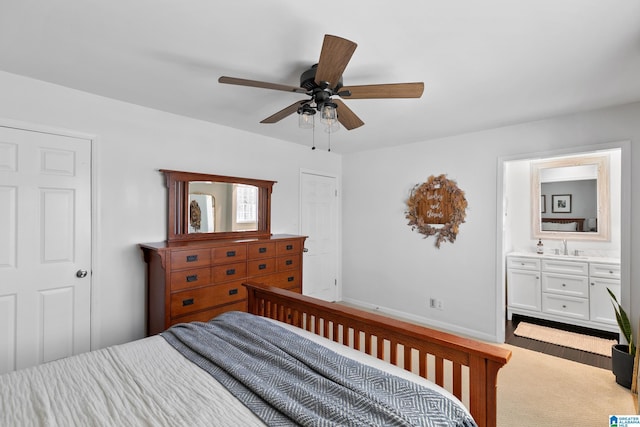 bedroom with ceiling fan, ensuite bathroom, a sink, and baseboards