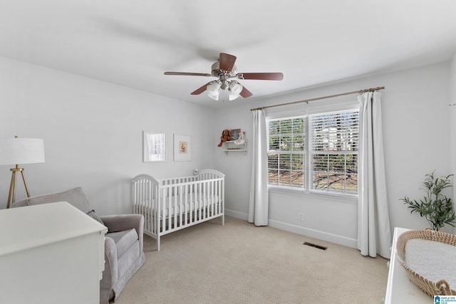 bedroom featuring carpet, visible vents, ceiling fan, a nursery area, and baseboards