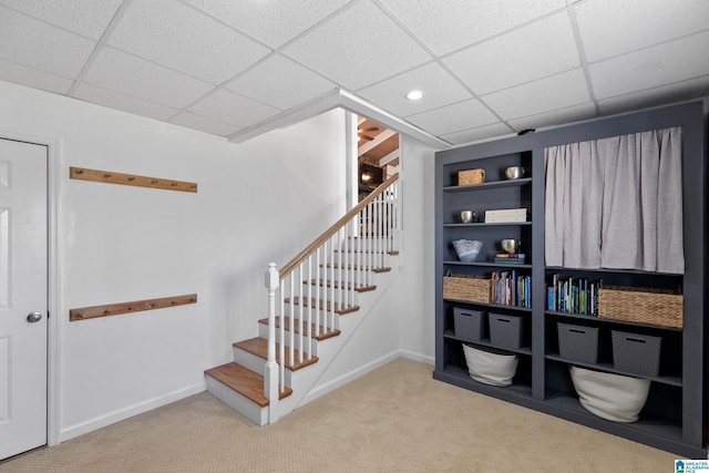 stairs featuring carpet flooring, a paneled ceiling, and baseboards