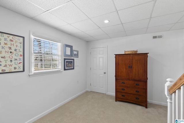 unfurnished bedroom with baseboards, visible vents, a drop ceiling, and light colored carpet