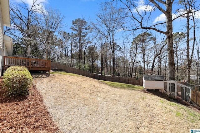 view of yard featuring a fenced backyard, a wooden deck, and an outdoor structure