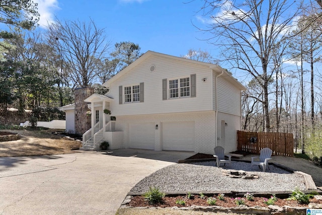 view of side of property featuring driveway, a garage, fence, and brick siding