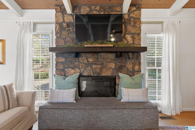 room details with a stone fireplace, beamed ceiling, wooden ceiling, and visible vents