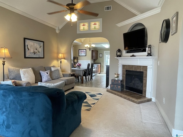 living room with arched walkways, visible vents, vaulted ceiling, a tiled fireplace, and crown molding