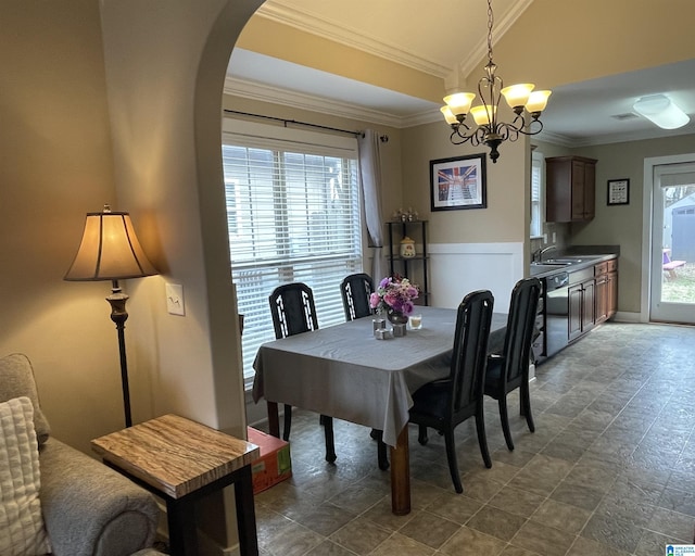 dining area featuring crown molding, a chandelier, arched walkways, and a wealth of natural light