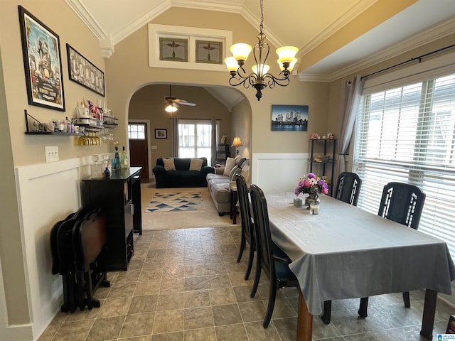 dining space featuring a wainscoted wall, arched walkways, vaulted ceiling, and crown molding