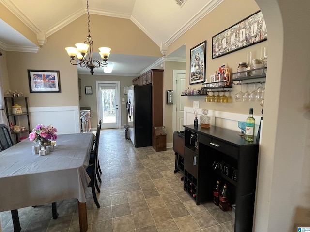 dining space featuring arched walkways, crown molding, lofted ceiling, an inviting chandelier, and baseboards