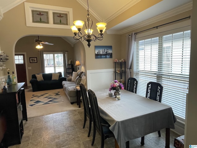 dining room with arched walkways, lofted ceiling, a wainscoted wall, ceiling fan with notable chandelier, and ornamental molding