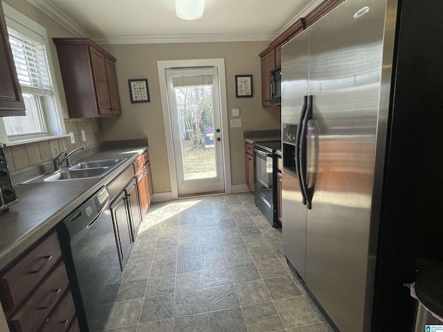 kitchen with decorative backsplash, dark countertops, crown molding, black appliances, and a sink