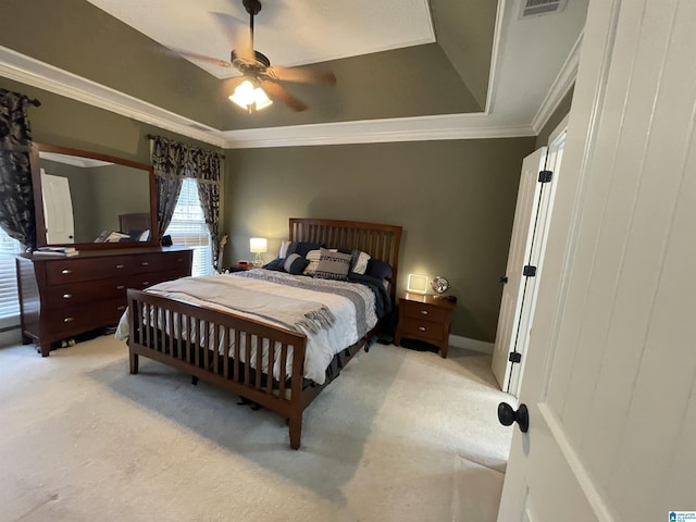 bedroom with ceiling fan, ornamental molding, a raised ceiling, and light colored carpet