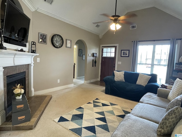 living room featuring arched walkways, visible vents, carpet flooring, vaulted ceiling, and a tile fireplace