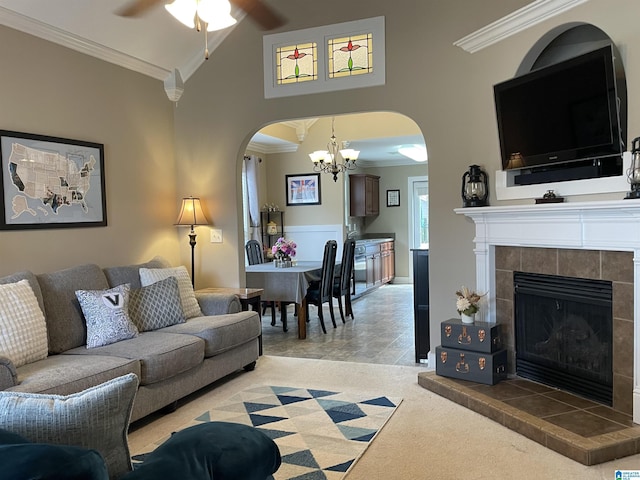 living area featuring light carpet, arched walkways, a tiled fireplace, ornamental molding, and high vaulted ceiling