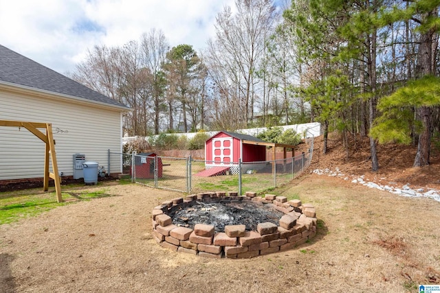 view of yard featuring a storage shed, an outdoor fire pit, an outbuilding, a gate, and fence