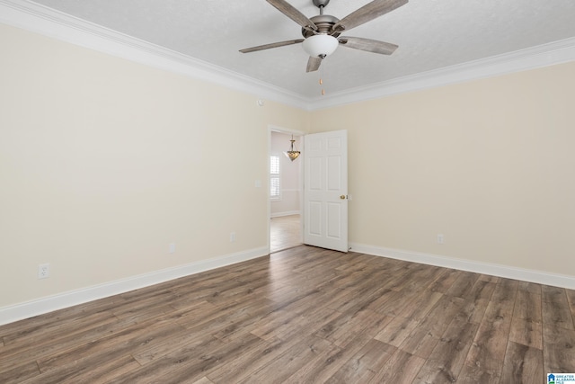 empty room with baseboards, wood finished floors, a ceiling fan, and crown molding