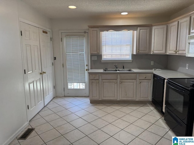 kitchen featuring light tile patterned floors, light countertops, visible vents, a sink, and black appliances