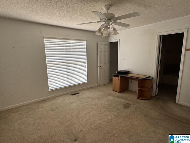 interior space featuring a textured ceiling, carpet floors, a ceiling fan, and baseboards