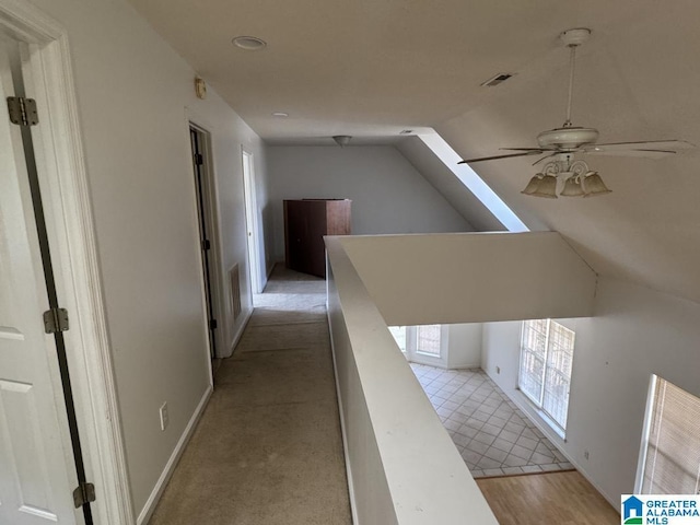 corridor with lofted ceiling, baseboards, visible vents, and an upstairs landing