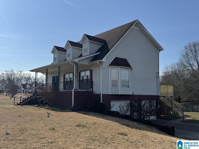 view of property exterior featuring a garage, covered porch, stairway, and a yard