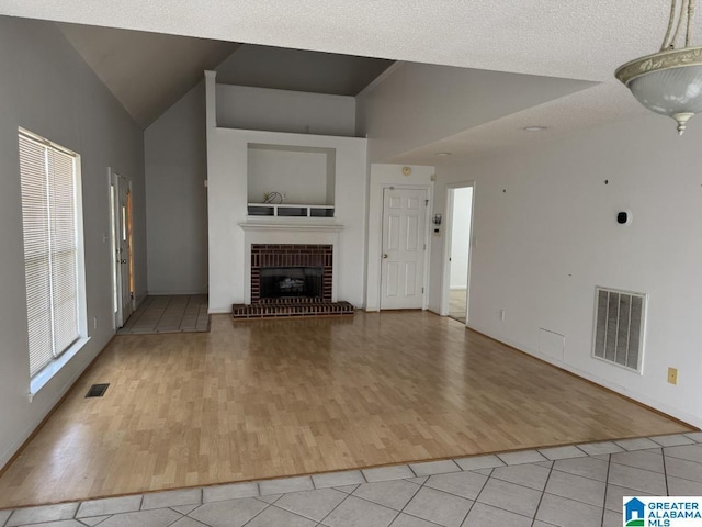 unfurnished living room featuring high vaulted ceiling, visible vents, a fireplace, and light tile patterned floors