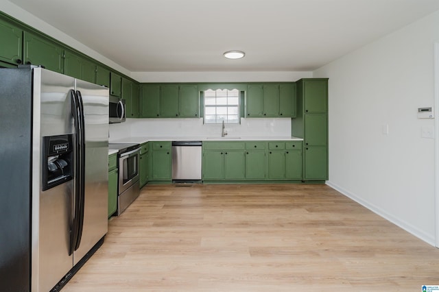 kitchen featuring appliances with stainless steel finishes, light countertops, green cabinetry, and a sink