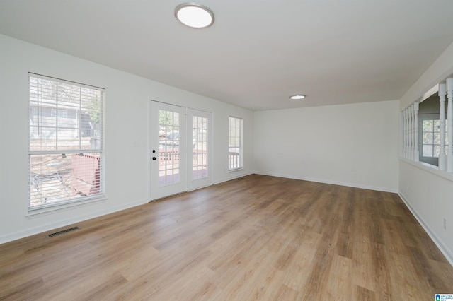 unfurnished room featuring light wood-type flooring, baseboards, and visible vents