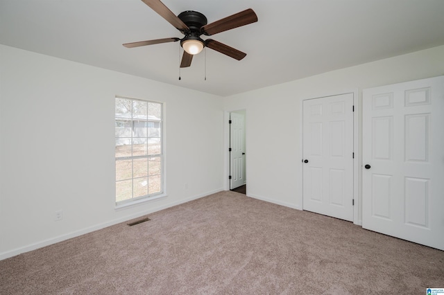 unfurnished bedroom with a ceiling fan, carpet flooring, visible vents, and baseboards