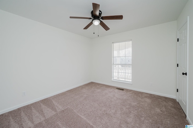 carpeted spare room featuring a ceiling fan, visible vents, and baseboards