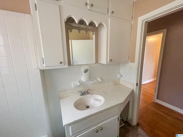 bathroom featuring decorative backsplash, vanity, baseboards, and wood finished floors