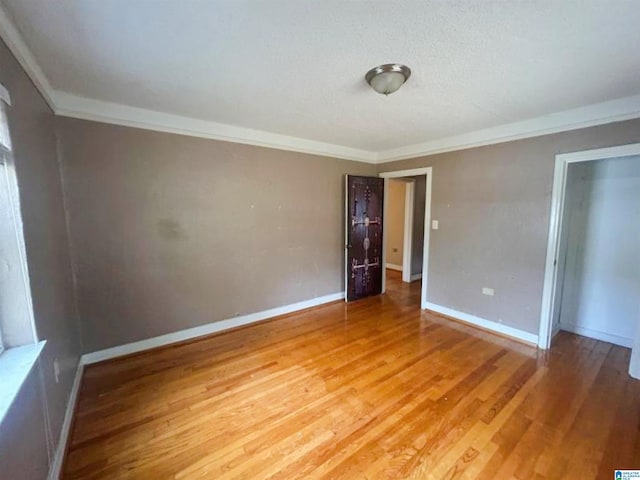 empty room featuring ornamental molding, baseboards, and light wood finished floors