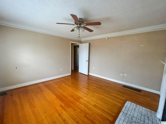 unfurnished room featuring a textured ceiling, visible vents, baseboards, light wood-type flooring, and crown molding