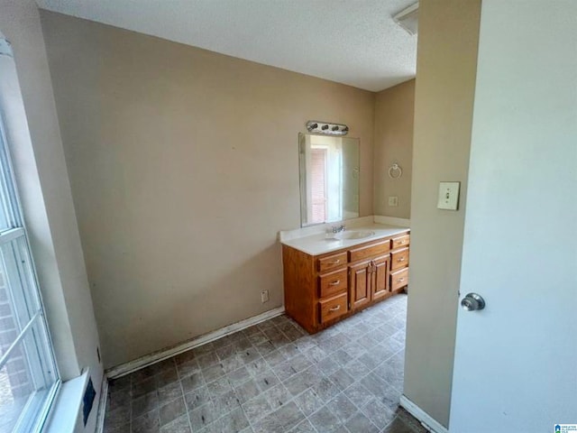 bathroom with vanity, baseboards, and a textured ceiling