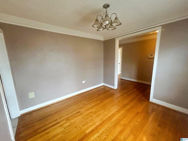 empty room with light wood-style floors, crown molding, baseboards, and an inviting chandelier